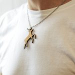 The wooden christmas necklace with shape of deer on the man's neck in a white t-shirt