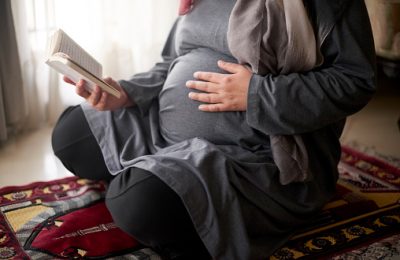 Quran, muslim and pregnant woman praying to Allah, god or holy spirit for islamic religion, faith and baby support. Spiritual book, maternity prayer hope and Islamic person worship during pregnancy
