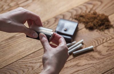 hand rolling cigarettes and tobacco on wood
