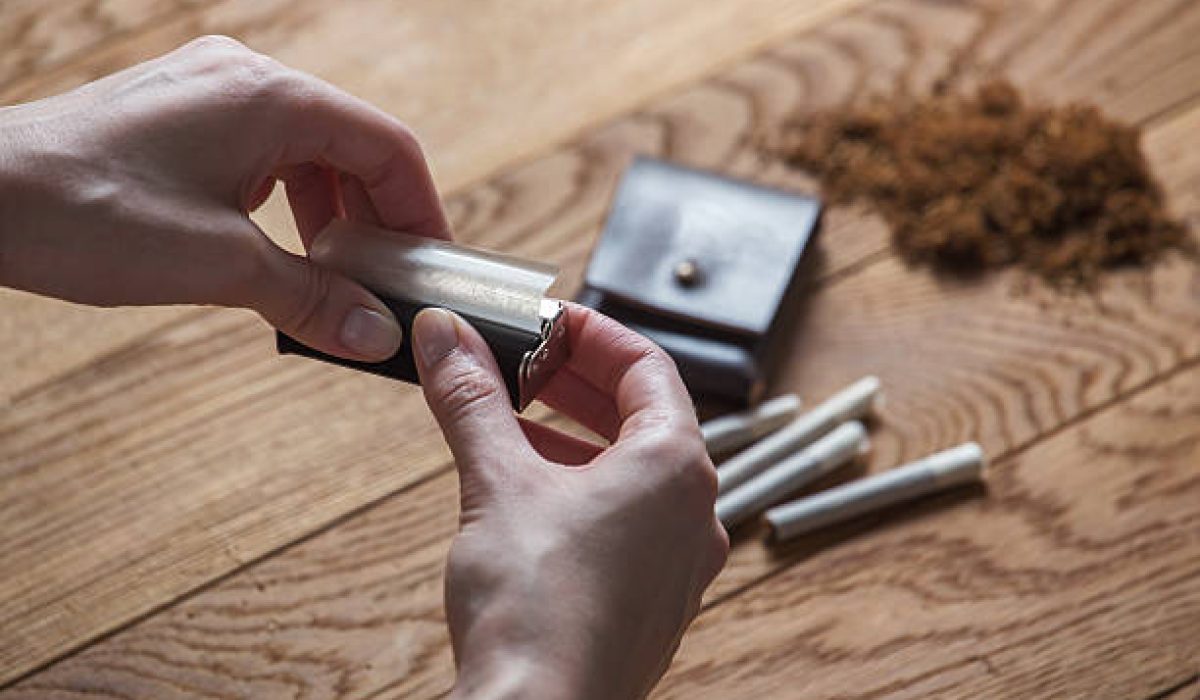 hand rolling cigarettes and tobacco on wood