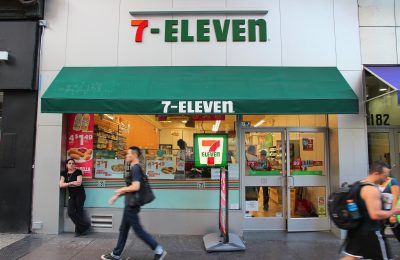 New York, United States - July 3, 2013: People walk past 7-Eleven convenience store in New York. 7-Eleven is world's largest operator, franchisor and licensor of convenience stores, with more than 46,000 shops.